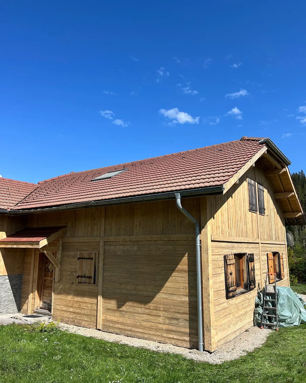 Façade de ferme en bois après sablage, bois blond et volets restaurés
